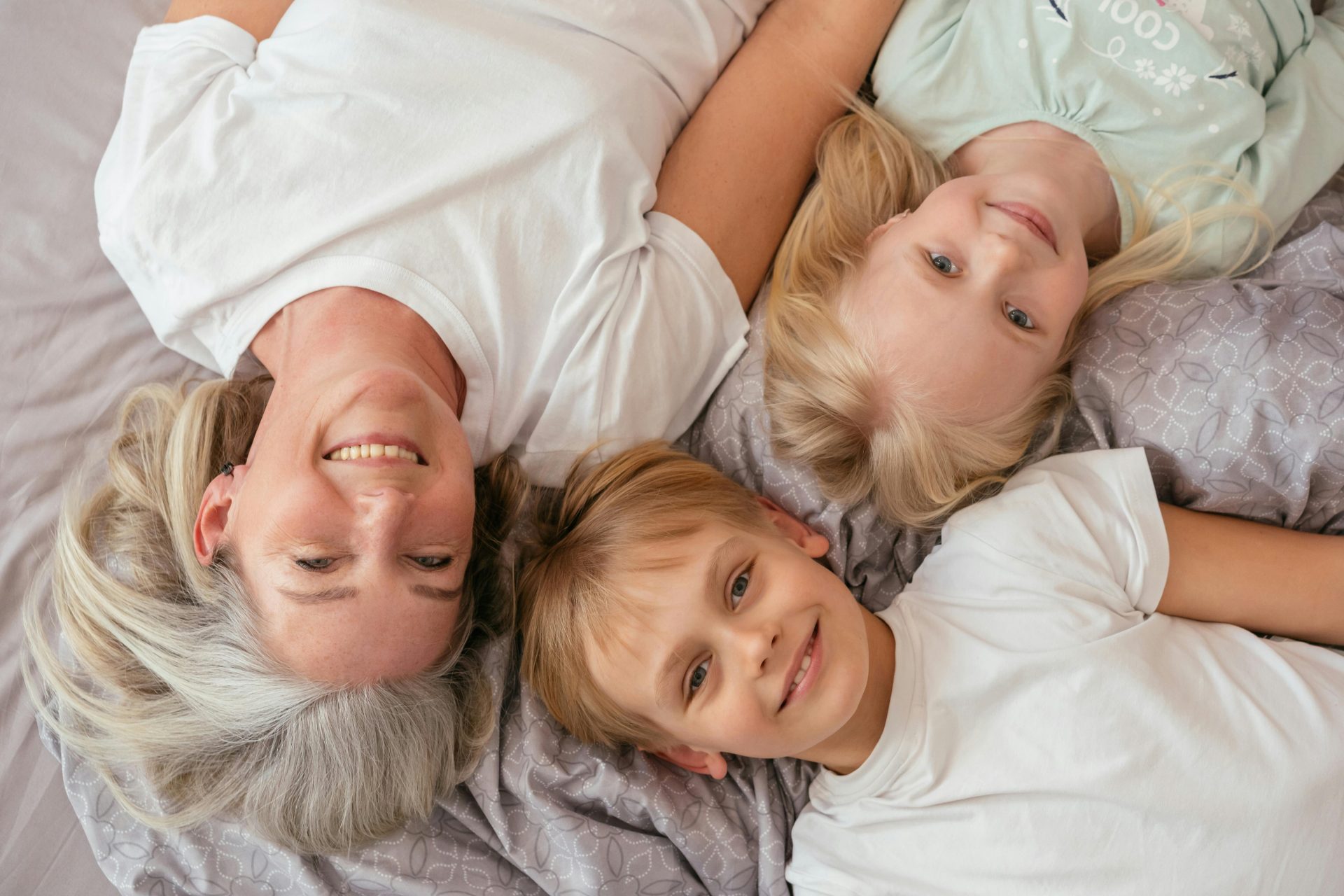 Grandmother and grandchildren smiling and lying together indoors.