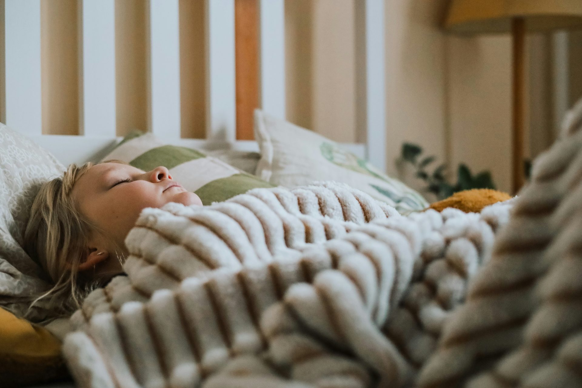 a little girl laying in bed under a blanket